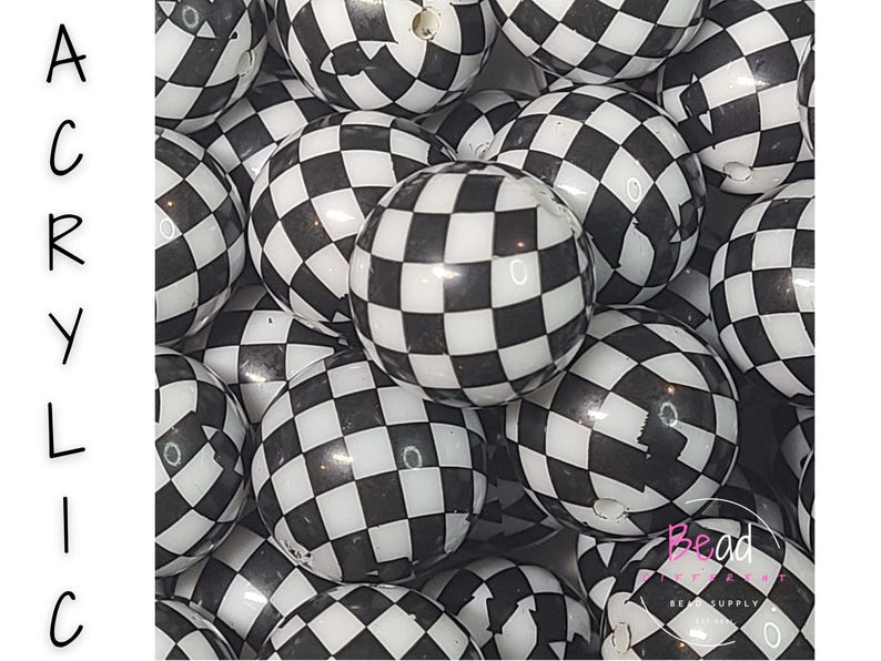 May include: A close-up of a pile of black and white checkered acrylic beads. The beads are round and have a glossy finish. The word "ACRYLIC" is written vertically in black letters on the left side of the image.