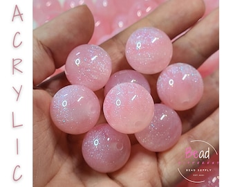 Puede incluir: Una colección de cuentas acrílicas redondas de color rosa claro con un acabado brillante. La palabra ACRYLIC está impresa verticalmente en el lado izquierdo y el logotipo de Bead Different Bead Supply es visible en la esquina inferior derecha.