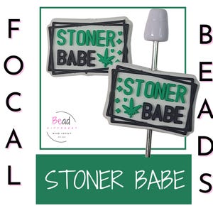 Op de afbeelding: Twee witte en zwarte Stoner Babe-bedels met groene accenten en een cannabisbladontwerp. De bedels zitten op een zilveren stok met een witte bovenkant. De afbeelding bevat ook de tekst "STONER BABE" in een groene doos.