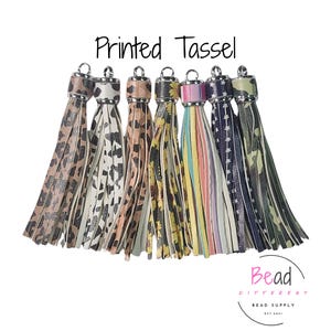 May include: A collection of printed tassels in various patterns, including leopard print, floral, and stars. Each tassel has a silver-tone cap and a loop for attaching to a keychain or other craft project. The text "Printed Tassel" is at the top.