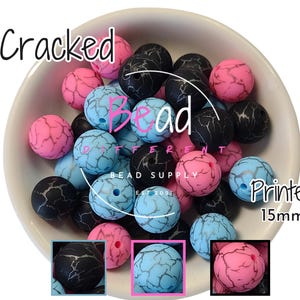 May include: A bowl of 15mm cracked printed silicone beads in black, pink, and blue. The beads have a marbled effect.