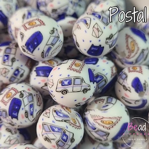 May include: White round beads with a postal theme. The beads feature illustrations of stamps, mail trucks, and envelopes in blue, black, and yellow. The word "Postal" is written in white script. The beads are for crafting.