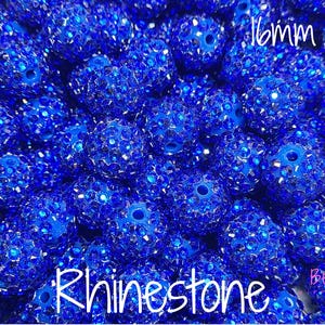 Puede incluir: Primer plano de un montón de cuentas de pedrería azules brillantes. Las cuentas miden 16 mm y están cubiertas de pequeños brillantes reflectantes. La palabra "Rhinestone" está escrita en blanco en la parte inferior.