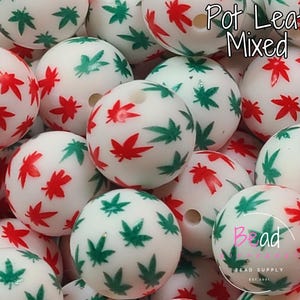 May include: White round beads with red and green pot leaf designs. The beads are mixed together and have a hole through the center for stringing. The text "Pot Leaf Mixed" is visible in the image.