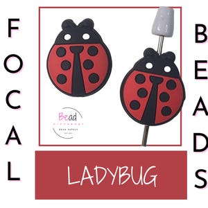 Op de afbeelding: Twee lieveheersbeestje-vormige focuskralen. Eén kraal is los, de andere is bevestigd aan een zilverkleurige pin. De lieveheersbeestjes zijn rood met zwarte details en hebben zes zwarte stippen. Het woord "LADYBUG" staat in een rode rechthoek.