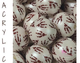 May include: A collection of round, off-white acrylic beads featuring a repeating dark brown animal paw print pattern. The word ACRYLIC is printed vertically on the left side, and the text Bead Supply is visible in the bottom right corner.