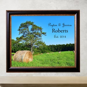 May include: A framed print with a photograph of a field with hay bales and a large tree. The text "Peyton & Jessica Roberts Est. 2014" is printed on the image.