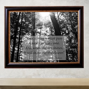 May include: Black and white photo of a forest with sunbeams shining through the trees. The quote "Even darkness must pass. A new day will come. And when the sun shines, it will shine out the clearer." by J.R.R. Tolkien is printed on the image.
