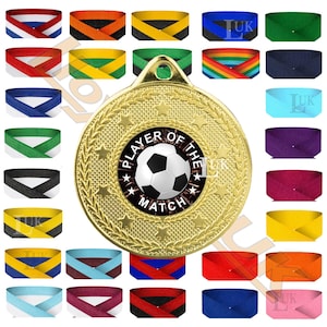 May include: A gold football medal with a central design featuring a black and white football and the text "PLAYER OF THE MATCH". The image also shows a selection of colourful ribbons in various shades, including blue, red, and green.