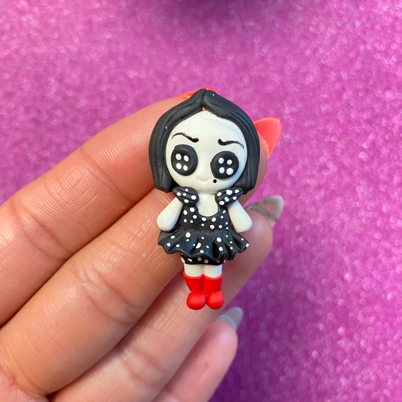 May include: A black and white polka dot dress with a black and white button eye doll with red shoes.