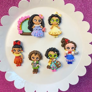 May include: Set of 7 handmade polymer clay doll charms featuring various characters with different hairstyles, clothing, and accessories. The dolls are colorful and have big eyes.