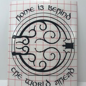 May include: Black and white vinyl decal with a circular design featuring a stylized gate with the text "Home is behind, the world ahead".