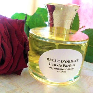 May include: A clear glass bottle of Belle D'Orient Eau de Parfum vaporisateur-spray, made in France. The bottle has a gold cap and a white label with black text.