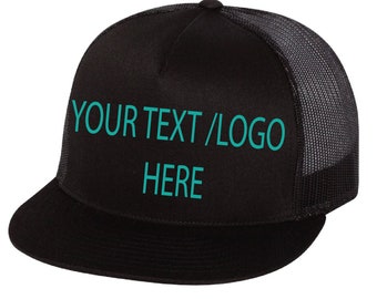May include: Black trucker hat with a black mesh back. The hat has the text "YOUR TEXT/LOGO HERE" embroidered in teal on the front.