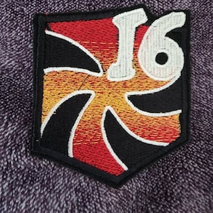 May include: A black, red, and yellow embroidered patch with a white swirl design and the number "16" in white.