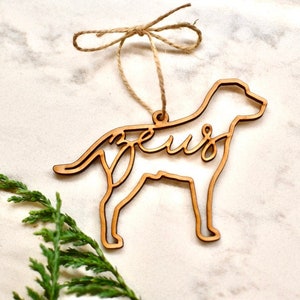 May include: Wooden dog-shaped Christmas ornament with the name "Zeus" cut out inside the silhouette.
