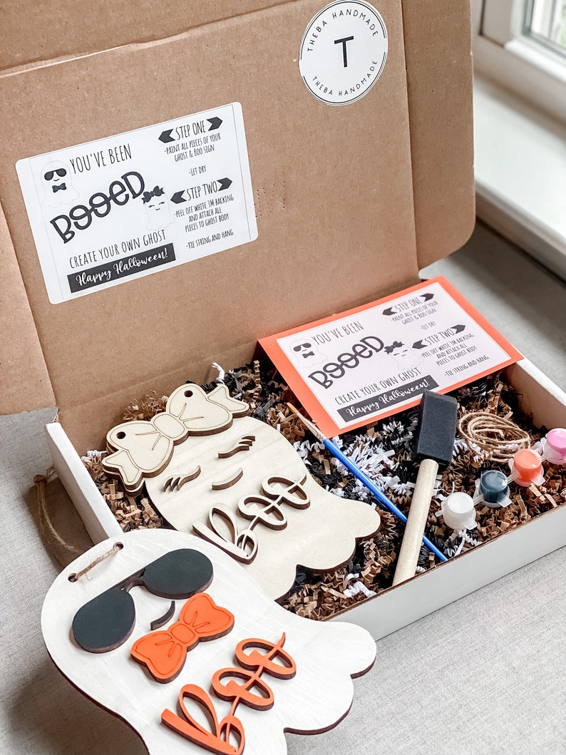 May include: A craft kit for creating two ghost decorations. The kit includes two unfinished wooden ghost shapes, paint, brushes, and instructions. The instructions say "You've Been Booed!" and "Create Your Own Ghost! Happy Halloween!"