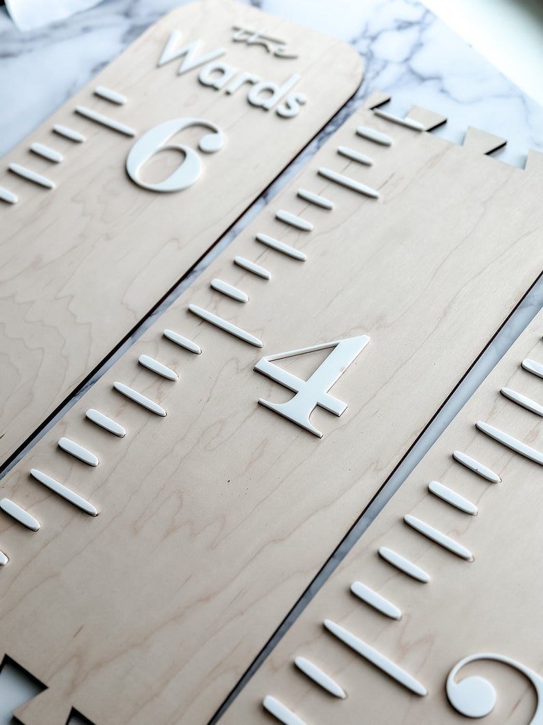 May include: A wooden growth chart with three sections, each with a white number and a ruler. The top section reads "The Wards" and has the number "6". The middle section has the number "4". The bottom section has the number "9".