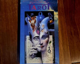 Puede incluir: Una carta de tarot azul y blanca con una ilustración colorida de un bufón con cabeza de tigre. La carta se titula "The Fool" y tiene el número "0" en la esquina superior derecha.