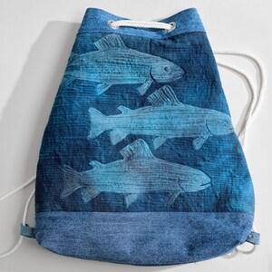 Könnte beinhalten: Eine blaue Kordeltasche mit einem Jeansboden. Die Tasche zeigt ein Design mit drei Fischen in Blautönen.