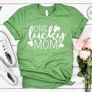 May include: Green t-shirt with white text that says "One lucky mom" and shamrock designs.