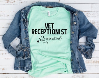 Könnte beinhalten: Ein hellgrünes T-Shirt mit dem Text "VET RECEPTIONIST #essential" in Schwarz. Ein schwarzes Stethoskop mit einem Herzen befindet sich über dem Text.