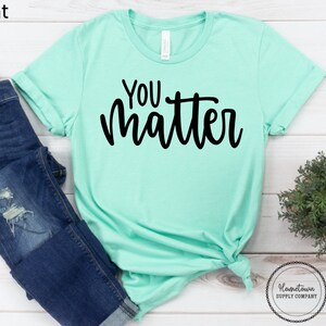 May include: A mint green t-shirt with the text "You Matter" in black lettering.
