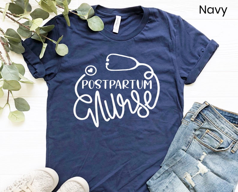 May include: Navy blue t-shirt with white text that reads "Postpartum Nurse" with a stethoscope graphic.