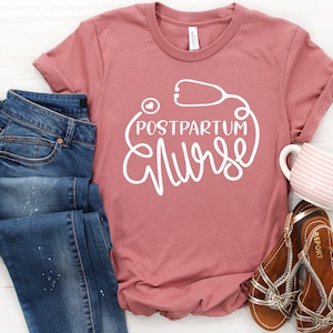 May include: A pink t-shirt with the text "Postpartum Nurse" in white lettering. The text is surrounded by a white outline of a stethoscope with a heart in the middle.