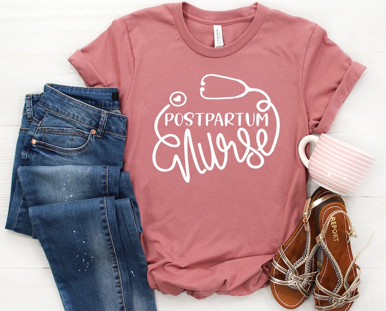 May include: A pink t-shirt with the text "Postpartum Nurse" in white lettering. The text is surrounded by a white outline of a stethoscope with a heart in the middle.