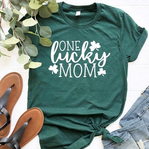 May include: A green t-shirt with white text that reads "One Lucky Mom" and shamrock designs.