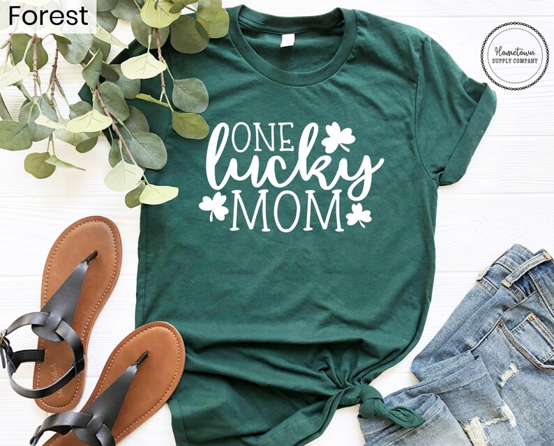 May include: A green t-shirt with the text "One Lucky Mom" in white lettering and shamrock designs.