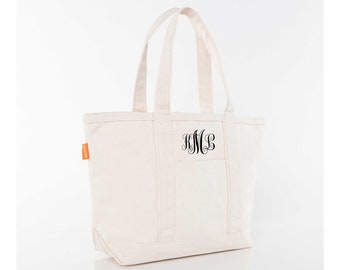 May include: A white canvas tote bag with a black monogram "KMC" embroidered on the front. The bag has a large pocket on the front and two long handles.