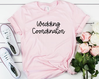 Puede incluir: Camiseta rosa con el texto "Wedding Coordinator" en letra cursiva negra.
