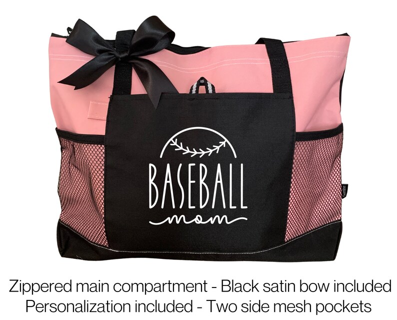 Może przedstawiać: R&oacute;żowa i czarna torba typu tote z czarną satynową kokardką. Torba ma czarną kieszeń z napisem "BASEBALL mom" w kolorze białym. Torba ma dwie boczne kieszenie siatkowe.