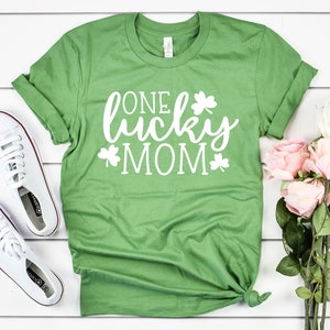 May include: Green t-shirt with white text that reads "One lucky mom" and shamrock designs.