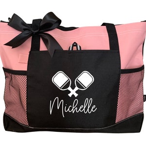 May include: Pink and black tote bag with a mesh pocket and a black pocket with a white paddleball design and the name "Michelle" in white text.