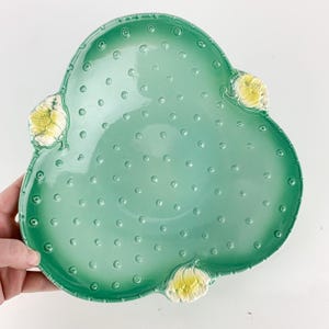 May include: A handmade wooden sign with the text "Welcome" in a playful font. The sign is painted white with a distressed finish, and features a decorative floral design in shades of pink and green. It measures approximately 12 inches wide.