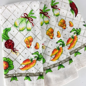 May include: Set of three white kitchen towels with a green, red, and yellow vegetable pattern. The towels feature a variety of vegetables, including onions, carrots, peppers, and beets.
