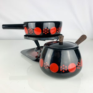 May include: Black and red enamel fondue set with a round pot and a smaller pot with a wooden handle. The pots have a polka dot pattern.