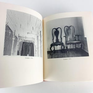 May include: A black and white photograph of an open book. One page shows a pair of dark pants hanging on a clothesline. The other page shows two antique wooden chairs. The text "Lexington 1974" appears below each image.