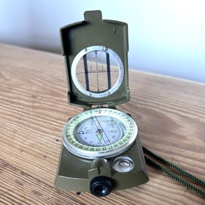 May include: A white ceramic mug with a black handle and the text "But First, Coffee" in a bold, black font. The mug is set against a neutral background, highlighting its simple design.