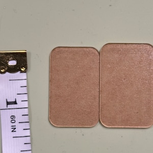 Puede incluir: Dos almohadillas adhesivas rectangulares, de color marrón claro y texturadas.