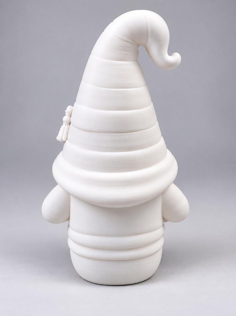 Back view of the white unpainted gnome figurine, showing the ridges of its large pointed hat and round body against a neutral gray background.