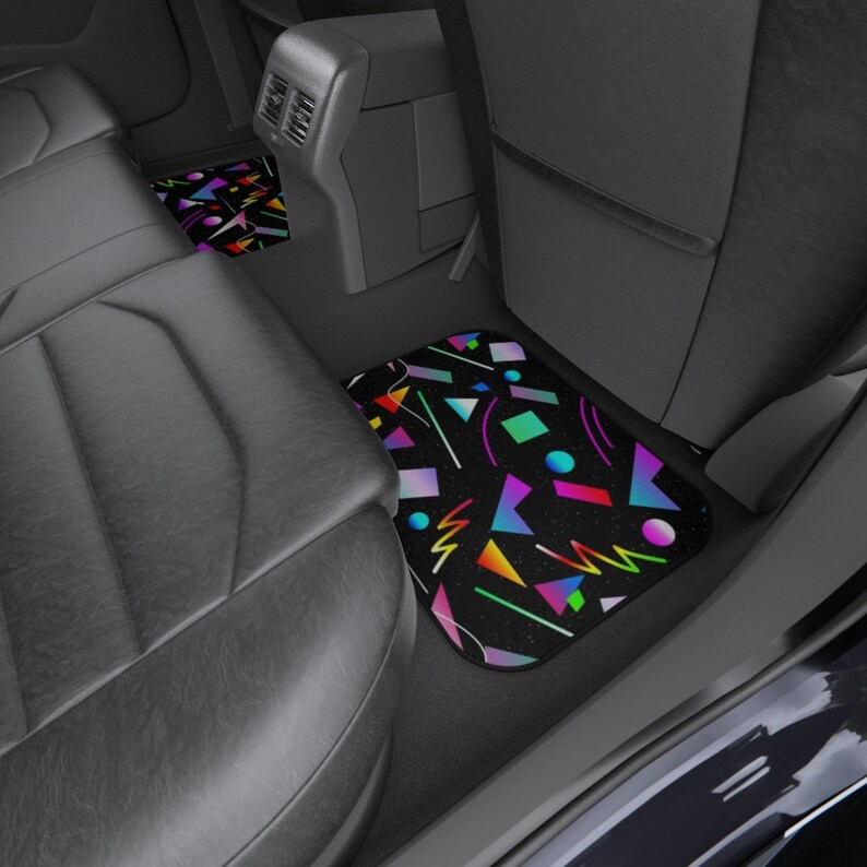 Op de afbeelding: Een set van twee autovloermatten met een geometrisch patroon in felle kleuren op een zwarte achtergrond. De matten zijn gemaakt van een duurzaam materiaal en zijn ontworpen om het interieur van uw auto te beschermen.