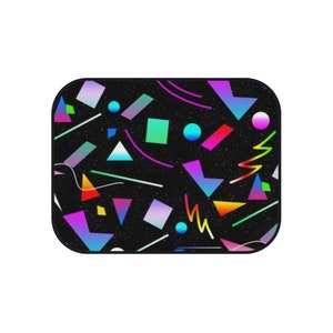 Op de afbeelding: Een zwarte achtergrond met een kleurrijk geometrisch patroon. Het patroon bevat driehoeken, vierkanten, cirkels en lijnen in tinten roze, blauw, groen, geel en oranje.