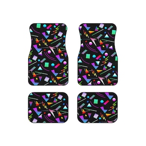 Op de afbeelding: Set van vier zwarte autovloermatten met een geometrisch patroon in felle kleuren, waaronder roze, blauw, groen, geel en oranje.