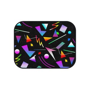 Op de afbeelding: Een zwarte achtergrond met een geometrisch patroon van kleurrijke vormen, waaronder driehoeken, vierkanten en lijnen. De vormen zijn in tinten roze, blauw, groen, geel en oranje.