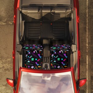 Puede incluir: El interior de un coche rojo con asientos de cuero negro y dos fundas de asiento con estampado geom&eacute;trico de colores.