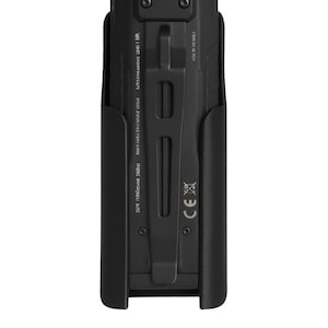 Puede incluir: Dispositivo rectangular negro con clip, posiblemente una cámara o dispositivo de grabación, en una funda negra. El dispositivo tiene una ranura central, dos botones circulares y texto en el lateral. La marca CE es visible.